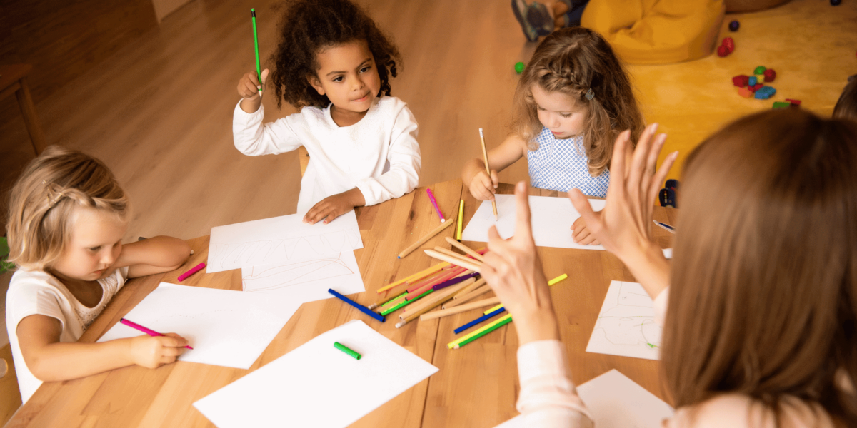 A teacher holds up her hands as three young children practice math